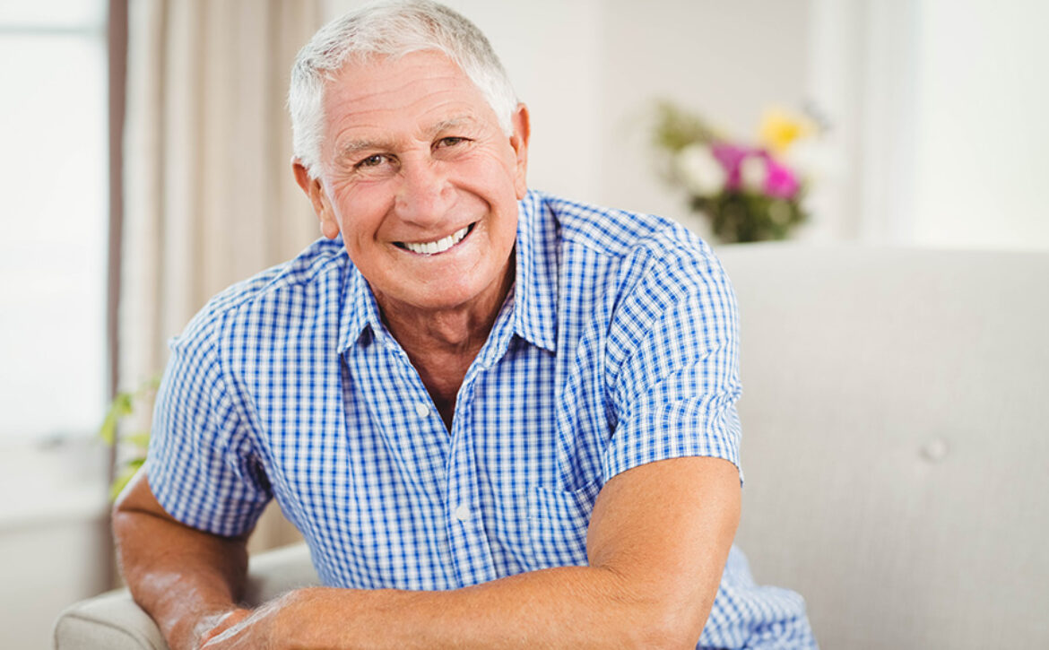 Senior man looking at camera and smiling in living room